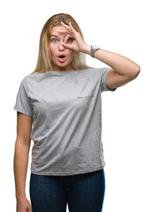 Fototapeta premium Young caucasian woman over isolated background doing ok gesture shocked with surprised face, eye looking through fingers. Unbelieving expression.