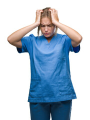 Young caucasian nurse woman wearing surgeon uniform over isolated background suffering from headache desperate and stressed because pain and migraine. Hands on head.