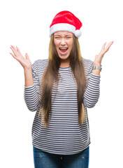 Fototapeta na wymiar Young beautiful caucasian woman wearing christmas hat over isolated background celebrating mad and crazy for success with arms raised and closed eyes screaming excited. Winner concept