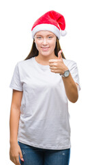 Young beautiful caucasian woman wearing christmas hat over isolated background doing happy thumbs up gesture with hand. Approving expression looking at the camera with showing success.