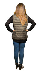 Beautiful middle age woman wearing winter vest standing backwards looking away with arms on body