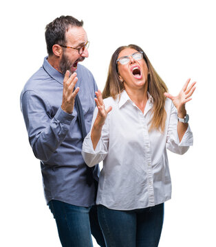 Middle age hispanic couple in love wearing glasses over isolated background crazy and mad shouting and yelling with aggressive expression and arms raised. Frustration concept.