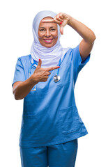 Middle age senior arab nurse woman wearing hijab over isolated background smiling making frame with hands and fingers with happy face. Creativity and photography concept.