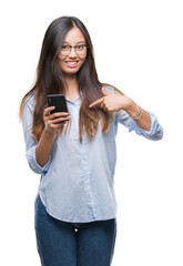 Fototapeta premium Young asian woman texting using smartphone over isolated background with surprise face pointing finger to himself