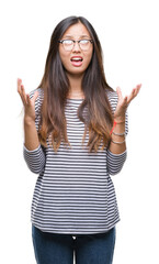 Young asian woman wearing glasses over isolated background crazy and mad shouting and yelling with aggressive expression and arms raised. Frustration concept.