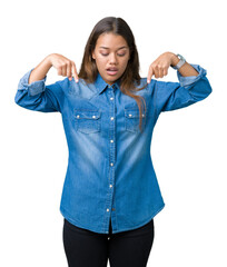 Young beautiful brunette woman wearing blue denim shirt over isolated background Pointing down with fingers showing advertisement, surprised face and open mouth