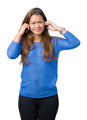 Obraz na płótnie Canvas Young beautiful brunette woman wearing blue sweater over isolated background covering ears with fingers with annoyed expression for the noise of loud music. Deaf concept.
