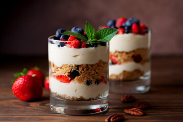 Dessert in a glasses with berries, mint, whipped cream and biscuit on wooden table. Healthy food, vegan, sugar, gluten and lactose free.