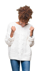 Beautiful young african american woman wearing winter sweater over isolated background very happy and excited doing winner gesture with arms raised, smiling and screaming for success. Celebration
