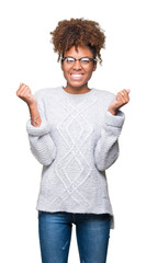 Beautiful young african american woman wearing winter sweater over isolated background celebrating surprised and amazed for success with arms raised and open eyes. Winner concept.