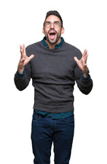 Fototapeta premium Young handsome man wearing glasses over isolated background crazy and mad shouting and yelling with aggressive expression and arms raised. Frustration concept.