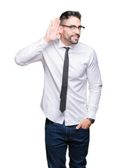 Young handsome business man wearing glasses over isolated background smiling with hand over ear listening an hearing to rumor or gossip. Deafness concept.