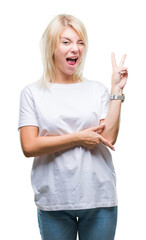 Young beautiful blonde woman wearing white t-shirt over isolated background smiling with happy face winking at the camera doing victory sign. Number two.