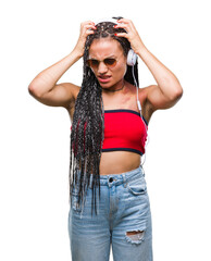 Young braided hair african american with birth mark wearing headphones over isolated background suffering from headache desperate and stressed because pain and migraine. Hands on head.