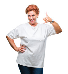 Atrractive senior caucasian redhead woman over isolated background smiling doing phone gesture with hand and fingers like talking on the telephone. Communicating concepts.