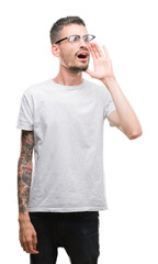 Young tattooed adult man shouting and screaming loud to side with hand on mouth. Communication concept.