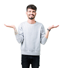 Young handsome man wearing sweatshirt over isolated background Smiling showing both hands open...