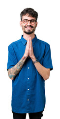 Young handsome man wearing glasses over isolated background praying with hands together asking for forgiveness smiling confident.