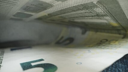 A five-euro banknote in the pocket of blue jeans. Dolly slider extreme close-up.