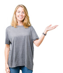 Fototapeta premium Beautiful young woman wearing oversize casual t-shirt over isolated background smiling cheerful presenting and pointing with palm of hand looking at the camera.