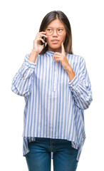 Young asian woman speaking on the phone over isolated background serious face thinking about...