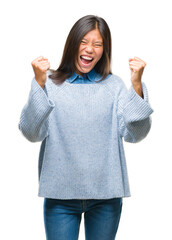 Young asian woman wearing winter sweater over isolated background very happy and excited doing winner gesture with arms raised, smiling and screaming for success. Celebration concept.