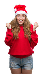 Young blonde woman wearing santa claus hat screaming proud and celebrating victory and success very excited, cheering emotion