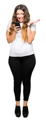 Fototapeta premium Young adult woman using smartphone very happy and excited, winner expression celebrating victory screaming with big smile and raised hands