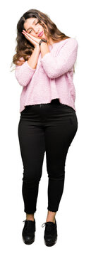 Young beautiful woman wearing pink sweater sleeping tired dreaming and posing with hands together while smiling with closed eyes.