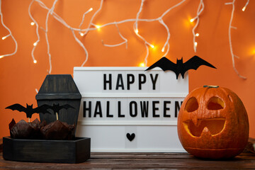 Happy Halloween white sign with black letters, pumpkin and halloween decoration.