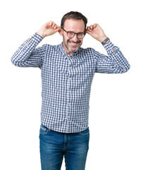 Fototapeta premium Handsome middle age elegant senior man wearing glasses over isolated background Smiling pulling ears with fingers, funny gesture. Audition problem