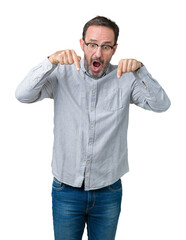 Fototapeta premium Handsome middle age elegant senior man wearing glasses over isolated background Pointing down with fingers showing advertisement, surprised face and open mouth