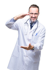 Middle age senior hoary doctor man wearing medical uniform isolated background gesturing with hands showing big and large size sign, measure symbol. Smiling looking at the camera. Measuring concept.