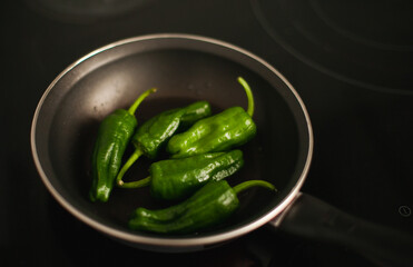 Cooking green small bell peppers - traditional Spanish tapas food in a frying pan