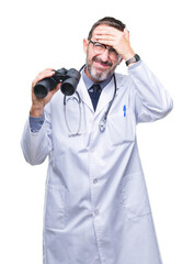 Middle age senior hoary doctor man looking through binoculars isolated background stressed with hand on head, shocked with shame and surprise face, angry and frustrated. Fear and upset for mistake.