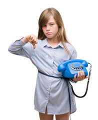 Young blonde toddler holding vintage telephone with angry face, negative sign showing dislike with thumbs down, rejection concept