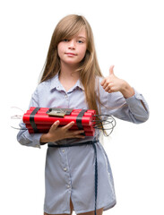 Young blonde child holding dynamite bomb happy with big smile doing ok sign, thumb up with fingers, excellent sign