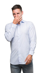 Handsome young businessman smelling something stinky and disgusting, intolerable smell, holding breath with fingers on nose. Bad smells concept.