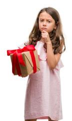 Brunette hispanic girl holding a gift serious face thinking about question, very confused idea