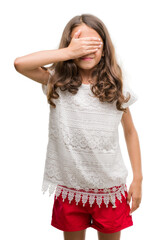 Brunette hispanic girl smiling and laughing with hand on face covering eyes for surprise. Blind concept.