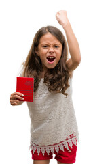 Brunette hispanic girl holding passport of Switzerland annoyed and frustrated shouting with anger, crazy and yelling with raised hand, anger concept