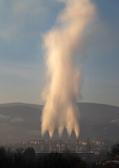 Huge cloud of smoke or steam rises above chimney of heating plant, city heating plant in Banja Luka and Ponir hill in background