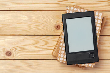 Portable e-book reader on wooden background top view