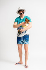 A man in a beach suit and flip flops with a Jack Russell Terrier in his arms