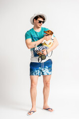 A man in a beach suit and flip flops with a Jack Russell Terrier in his arms