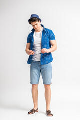 A man in casual summer clothes and a hat puts on or takes off sunglasses