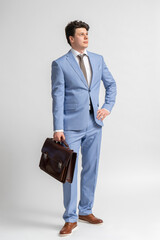 Young man in a blue business suit, white shirt and tie with a leather briefcase