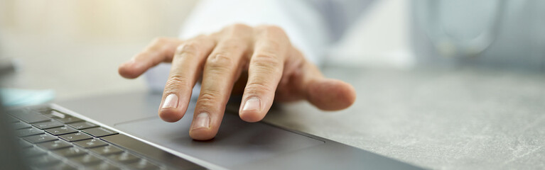 Male doctor hand using modern laptop in clinic