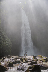 Young family father with daughter travellers explore waterfall in Bali, travel concept , vacation in Asia.