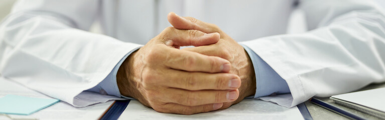 Male doctor putting hands on table with documents